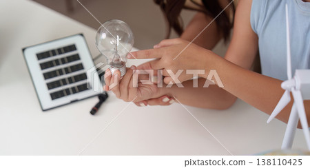 Child and parent examining a light bulb and solar panel Child and parent examining a light bulb and solar panel 138110425