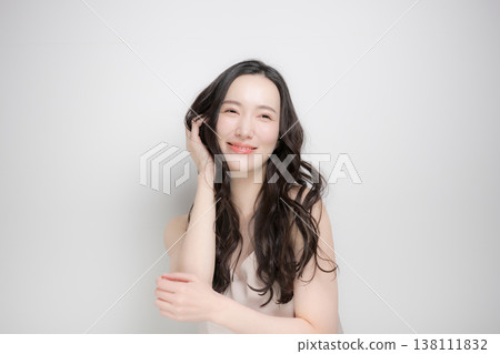 Hair care and beauty image of a woman with long permed hair, looking directly at the camera. Hair care and beauty image of a woman with long permed hair, looking directly at the camera. 138111832