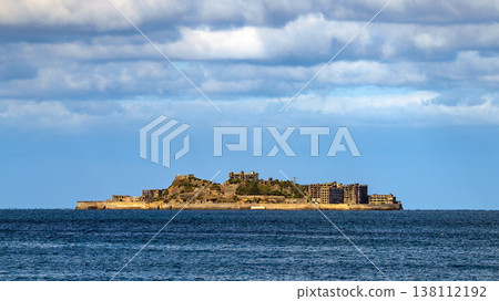 A panoramic view of Gunkanjima Island floating in the distant sea under a blue sky. 138112192