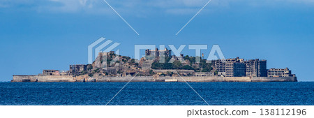 A panoramic view of Gunkanjima Island floating in the distant sea under a blue sky. 138112196