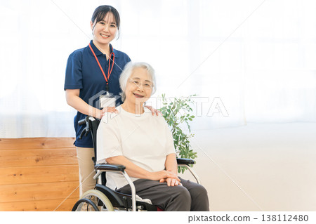 一位坐在輪椅上的老婦人和一位在養老院工作的女性工作人員。 一位坐在輪椅上的老婦人和一位在養老院工作的女性工作人員。 138112480