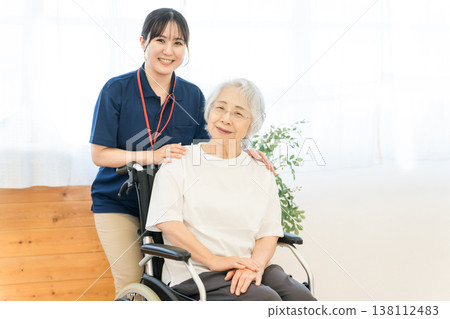 A senior woman in a wheelchair and a female staff member working at a nursing home. 138112483