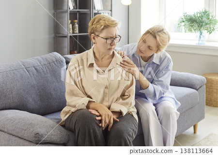 Senior upset mother and adult daughter sitting on sofa at home, helping offering comfort, caring  138113664