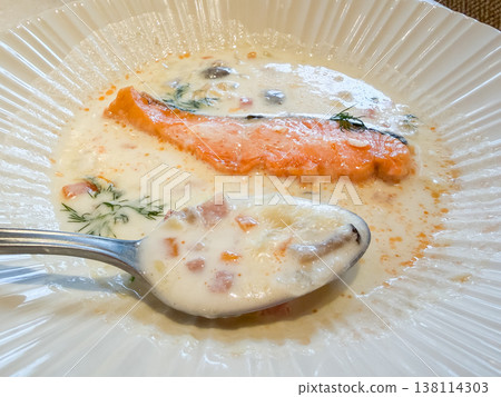 Clam chowder. A white stew containing clams and salmon fillets. A close-up of the stew. 138114303
