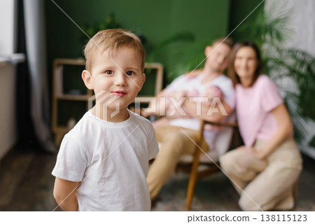 Adorable Boy Facing Camera With Family Behind 138115123