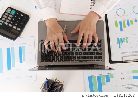 Accountant typing on laptop with financial documents 138115268