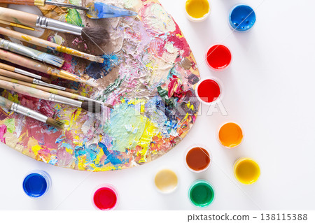 Artist's palette with colorful paint strokes, gouache jars and paintbrushes on white isolated background, top view, flat lay, object Artist's palette with colorful paint strokes, gouache jars and paintbrushes on white isolated background, top view, flat lay, object 138115388
