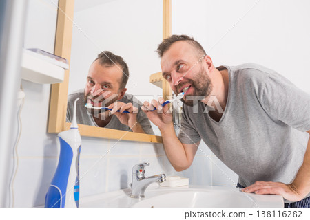 Man brushing his teeth in bathroom Man brushing his teeth in bathroom 138116282