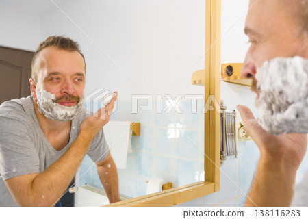 Guy shaving his beard in bathroom Guy shaving his beard in bathroom 138116283
