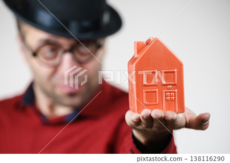 Man wearing funny eyeglasses holding house Man wearing funny eyeglasses holding house 138116290