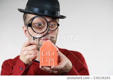 Man magnifying red house Man magnifying red house 138116291