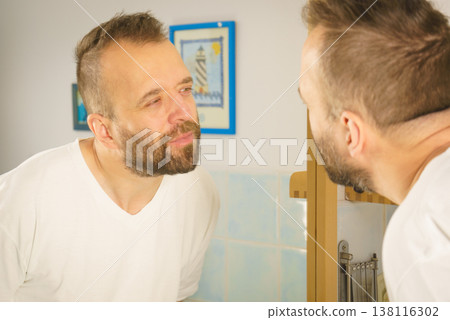 Man looking at himself in mirror 138116302