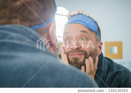 Happy man after sleep looking at mirror Happy man after sleep looking at mirror 138116303