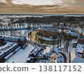Detailed aerial view of Huis Bergh Castle in winter. Historical medieval brick fortress surrounded by a frozen circular moat and snow covered grounds in a picturesque European town landscape. 138117152
