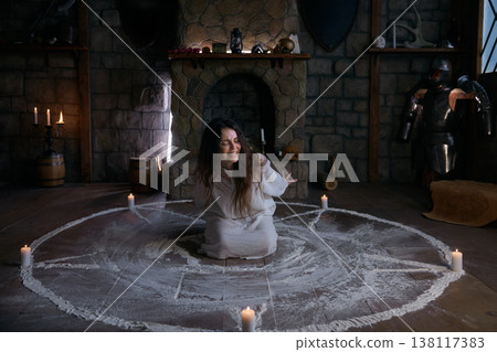 An anxious woman reaches out through chalk circle with candlelit surroundings An anxious woman reaches out through chalk circle with candlelit surroundings 138117383