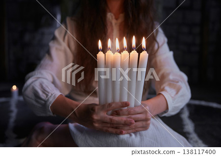 Crop of woman practitioner immersed in ritual using old books and ceremonial objects Crop of woman practitioner immersed in ritual using old books and ceremonial objects 138117400