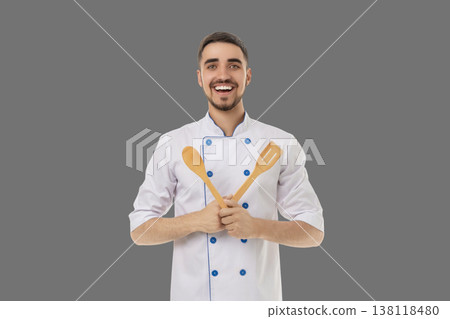 Occupation, Young man holds wooden spoons and smiles in the kitchen Occupation, Young man holds wooden spoons and smiles in the kitchen 138118480