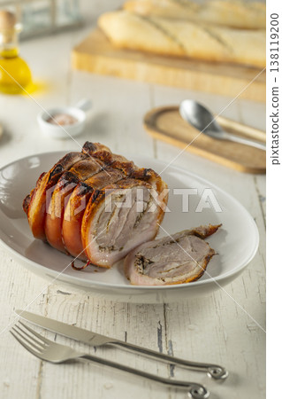 Traditional Italian porchetta with crispy skin on a white plate Traditional Italian porchetta with crispy skin on a white plate 138119200