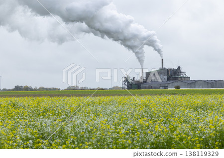 Industrial factory emitting smoke in blooming agricultural field Industrial factory emitting smoke in blooming agricultural field 138119329