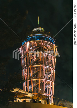 The illuminated observation tower and spiral staircase shine brightly against the night sky. The illuminated observation tower and spiral staircase shine brightly against the night sky. 138119788
