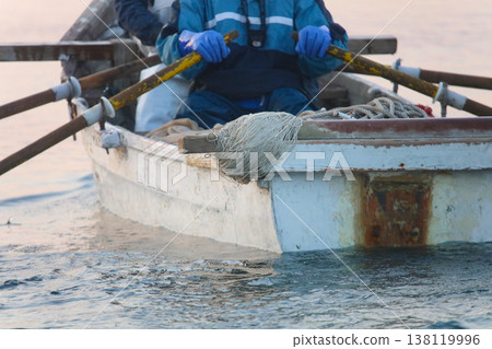 A fisherman rowing a boat 138119996