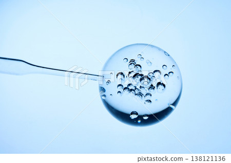 Abstract cosmetic lab. Pipette drawing clear liquid from spherical gel with bubbles 138121136