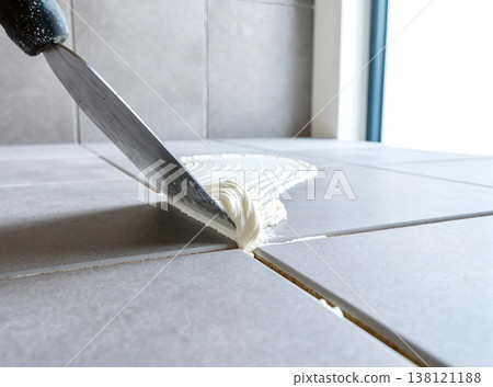Tiling grey floor with white grout and steaming mortar 138121188