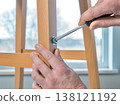 Hands Using Screwdriver to Assemble Wooden Chair at Home 138121192