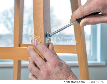 Hands Using Screwdriver to Assemble Wooden Chair at Home Hands Using Screwdriver to Assemble Wooden Chair at Home 138121192