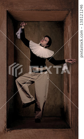 Fashion portrait man in ruffled collar and wide trousers dramatic pose inside box. 138121246