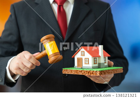 A man holds a house and a judge's gavel. A real estate court order. A home auction. Legal decisions impact ownership. Property disputes resolve through judicial process. 138121321