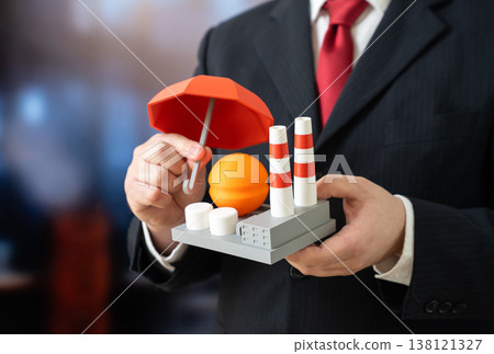 A businessman holds an umbrella over an industrial facility. Protecting the energy sector from drones and threats. Industrial insurance. Chemical sector. Risk mitigation and security planning 138121327