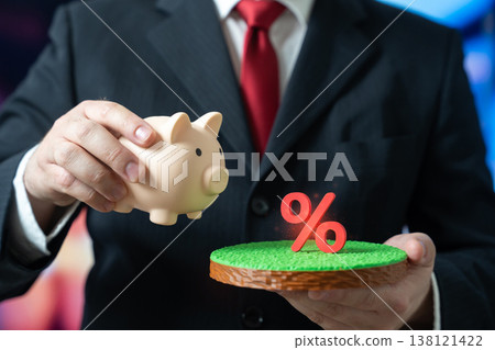 A businessman holds a piggy bank and a pasture with lucrative interest rates. A concept for profitable deposits and investments. Savings growth supports financial stability and long term wealth. A businessman holds a piggy bank and a pasture with lucrative interest rates. A concept for profitable deposits and investments. Savings growth supports financial stability and long term wealth. 138121422