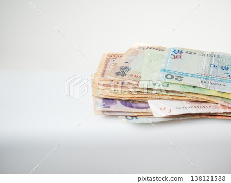 Stack of international banknotes on white background. Pile of various foreign currency cash. Global travel, business finance, saving, investment and economy concept for money management. Stack of international banknotes on white background. Pile of various foreign currency cash. Global travel, business finance, saving, investment and economy concept for money management. 138121588