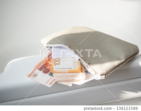 Leather cosmetic bag filled with paper money banknotes. Wealth and finance savings concept. Cash inside purse for personal budget management. Financial accumulation and economy theme. Leather cosmetic bag filled with paper money banknotes. Wealth and finance savings concept. Cash inside purse for personal budget management. Financial accumulation and economy theme. 138121589