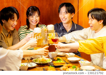 A young man and woman toast at an izakaya (Japanese pub). 138121792