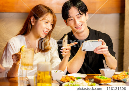 A man and a woman looking at their smartphones while drinking alcohol. 138121808