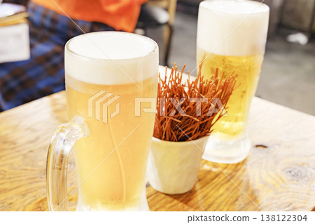 A mug of beer and snacks placed on the table in the izakaya. A mug of beer and snacks placed on the table in the izakaya. 138122304