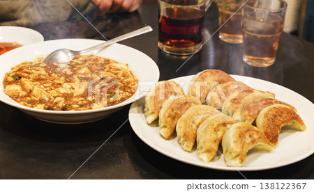 桌上擺放著一套正宗的中國菜，包括餃子和麻婆豆腐。 138122367