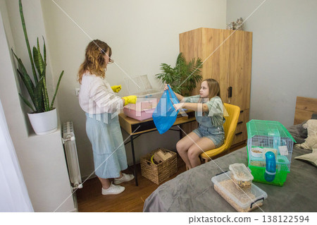 Mom and daughter are working together to set up a pet enclosure in a bedroom. Mom and daughter are working together to set up a pet enclosure in a bedroom. 138122594
