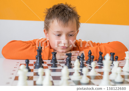 Smiling child boy playing chess at school indoors Smiling child boy playing chess at school indoors 138122680
