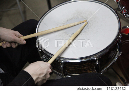 A musician holds drumsticks above a snare drum in a music studio. A musician holds drumsticks above a snare drum in a music studio. 138122682