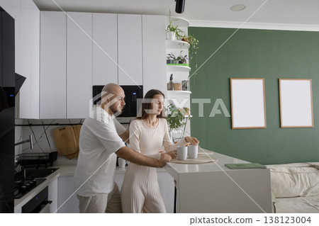 Pretty woman and man enjoying a cup of drink in the morning together at home in their kitchen.  138123004