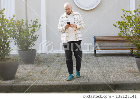 Young man walking and talking on phone outdoors Young man walking and talking on phone outdoors 138123141