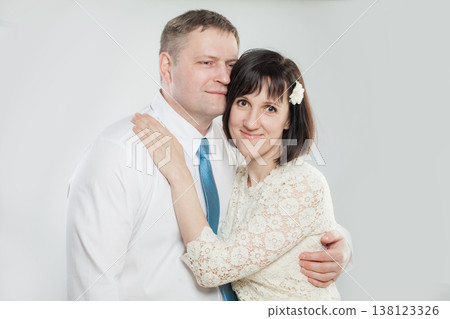 A couple poses together in a studio setting. They smile and display affection for each other. A couple poses together in a studio setting. They smile and display affection for each other. 138123326