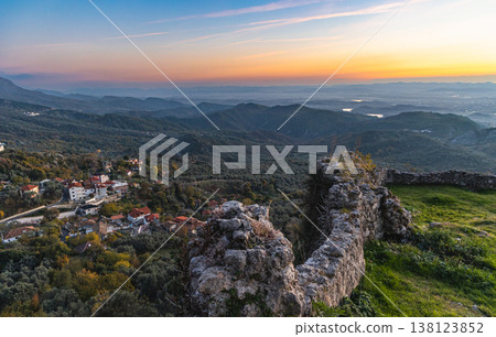 Rural countryside Albania. Mountain range with small village in the valley with sunset vibrant sky Rural countryside Albania. Mountain range with small village in the valley with sunset vibrant sky 138123852