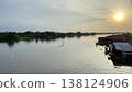 Boat Crossing Calm River at Golden Sunset with Riverside Houses 138124906