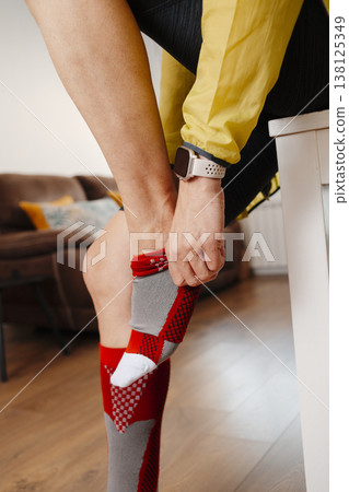 a man adjusts a compression sock before a run a man adjusts a compression sock before a run 138125349