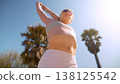 Active woman dressed in pink standing confidently amidst greenery 138125542