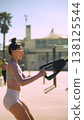 Female athlete exercising on handcycle machine near coastal scenery 138125544